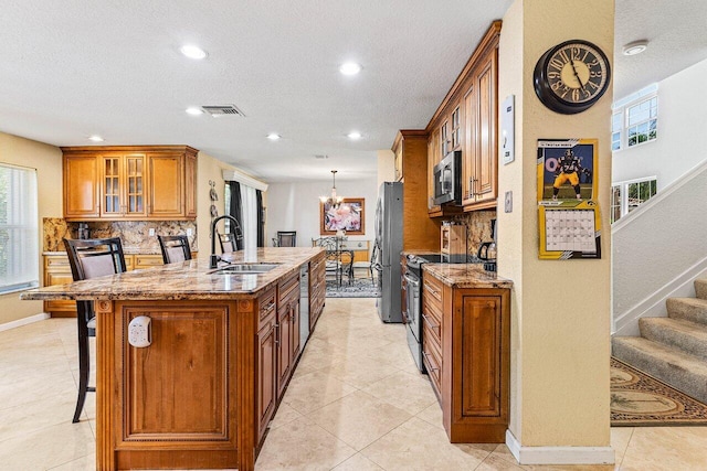 3995 Majestic Palm Way, Delray Beach, FL 33445 - kitchen with appliances with stainless steel finishes, a center island with sink, brown cabinetry, tasteful backsplash, and recessed lighting