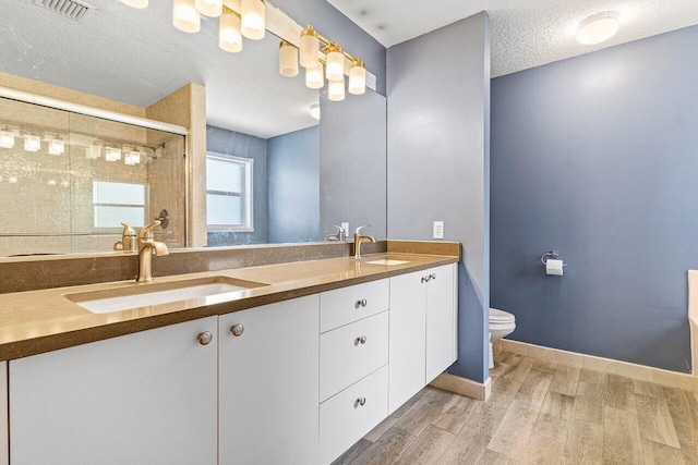3995 Majestic Palm Way, Delray Beach, FL 33445 - bathroom featuring double vanity, wood finished floors, a textured ceiling, and tiled shower