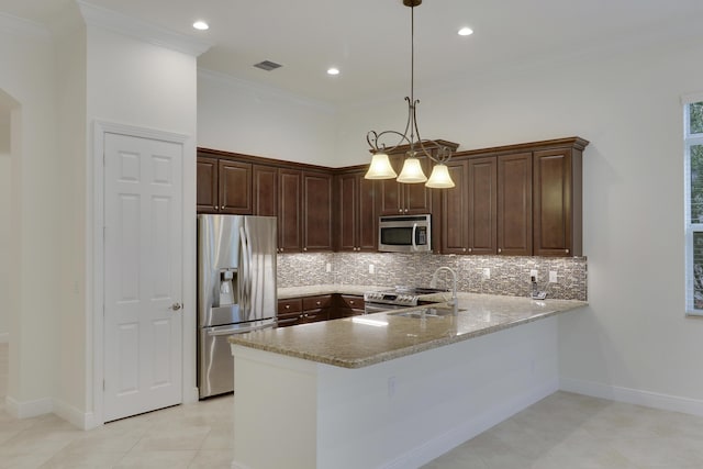 10479 SW Visconti Way, Port Saint Lucie, FL 34986 - kitchen with stainless steel appliances, a peninsula, tasteful backsplash, crown molding, and decorative light fixtures