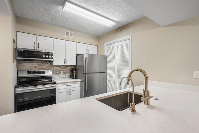 800 Scotia Dr Unit 102, Hypoluxo, FL 33462 - kitchen featuring stainless steel appliances, decorative backsplash, light countertops, white cabinetry, and a textured ceiling