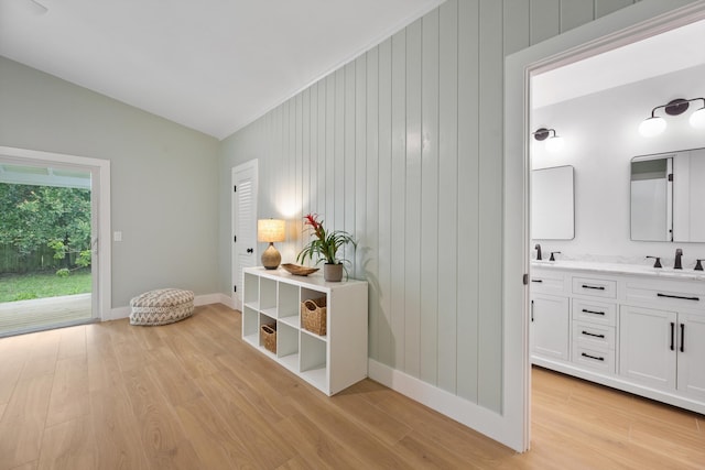1567 NE Sottong Ave, Jensen Beach, FL 34957 - corridor with light wood finished floors, vaulted ceiling, a sink, baseboards, and wood walls