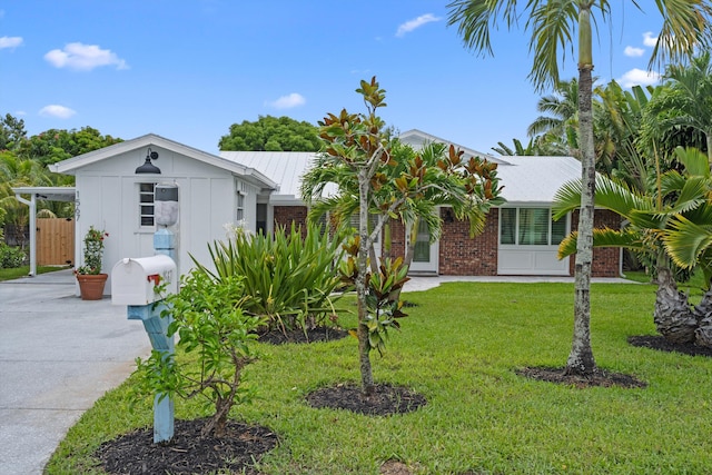 1567 NE Sottong Ave, Jensen Beach, FL 34957 - view of front of home with a front yard, concrete driveway, brick siding, and metal roof