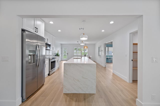 1567 NE Sottong Ave, Jensen Beach, FL 34957 - kitchen with stainless steel appliances, a sink, white cabinetry, light wood finished floors, and recessed lighting