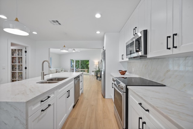 1567 NE Sottong Ave, Jensen Beach, FL 34957 - kitchen with stainless steel appliances, a sink, light wood-style flooring, white cabinets, and recessed lighting