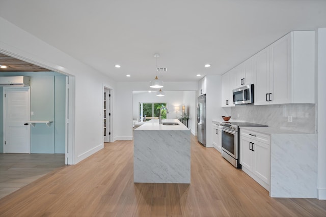 1567 NE Sottong Ave, Jensen Beach, FL 34957 - kitchen featuring stainless steel appliances, a sink, light wood finished floors, recessed lighting, and white cabinets
