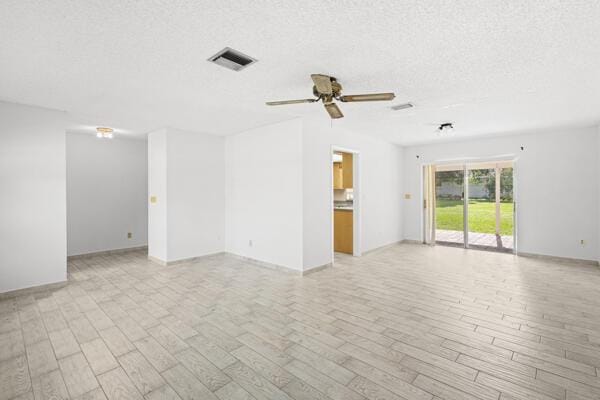 1830 Well Rd, Fort Pierce, FL 34945 - unfurnished living room with ceiling fan, light wood-style flooring, a textured ceiling, and baseboards
