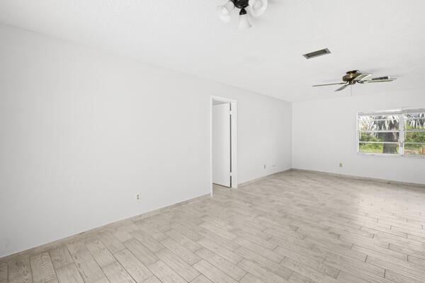 1830 Well Rd, Fort Pierce, FL 34945 - empty room with a ceiling fan, light wood finished floors, and baseboards