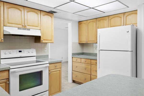 1830 Well Rd, Fort Pierce, FL 34945 - kitchen featuring white appliances, under cabinet range hood, light brown cabinets, and tasteful backsplash