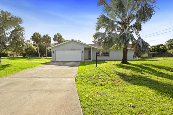 1830 Well Rd, Fort Pierce, FL 34945 - ranch-style home with a front lawn, a garage, concrete driveway, and stucco siding