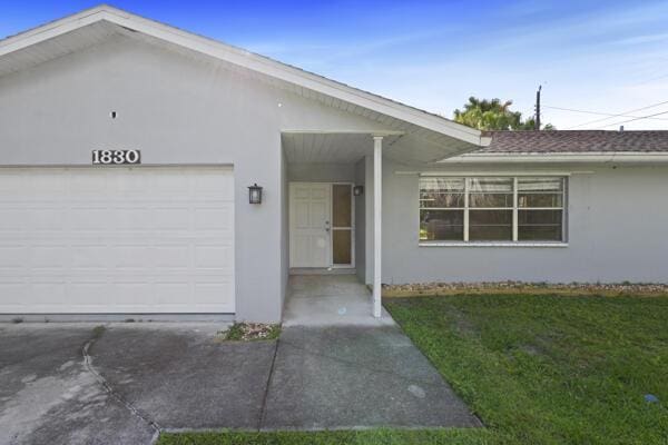 1830 Well Rd, Fort Pierce, FL 34945 - ranch-style home with stucco siding, an attached garage, a front lawn, and driveway