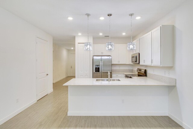 14556 Wiley Range Rd, Delray Beach, FL 33446 - kitchen with stainless steel appliances, light countertops, light wood-style floors, a peninsula, and pendant lighting