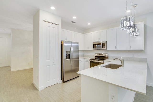 14556 Wiley Range Rd, Delray Beach, FL 33446 - kitchen featuring appliances with stainless steel finishes, a peninsula, light stone countertops, white cabinets, and hanging light fixtures