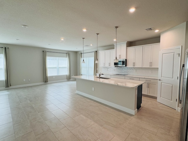 163 SW Pomeroy St, Stuart, FL 34997 - kitchen with stainless steel appliances, a sink, decorative backsplash, a center island with sink, and a textured ceiling
