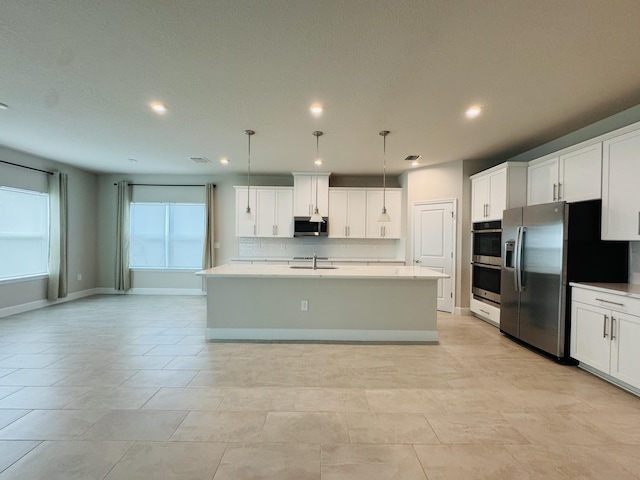 163 SW Pomeroy St, Stuart, FL 34997 - kitchen with stainless steel appliances, decorative backsplash, a sink, light countertops, and a center island with sink