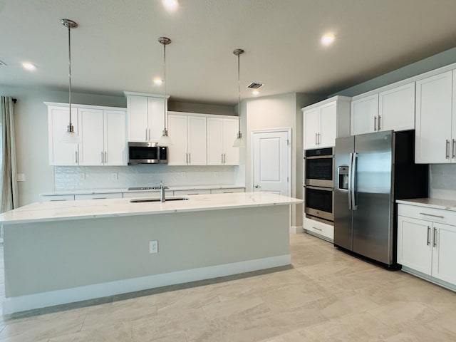 163 SW Pomeroy St, Stuart, FL 34997 - kitchen featuring stainless steel appliances, a sink, backsplash, an island with sink, and white cabinets