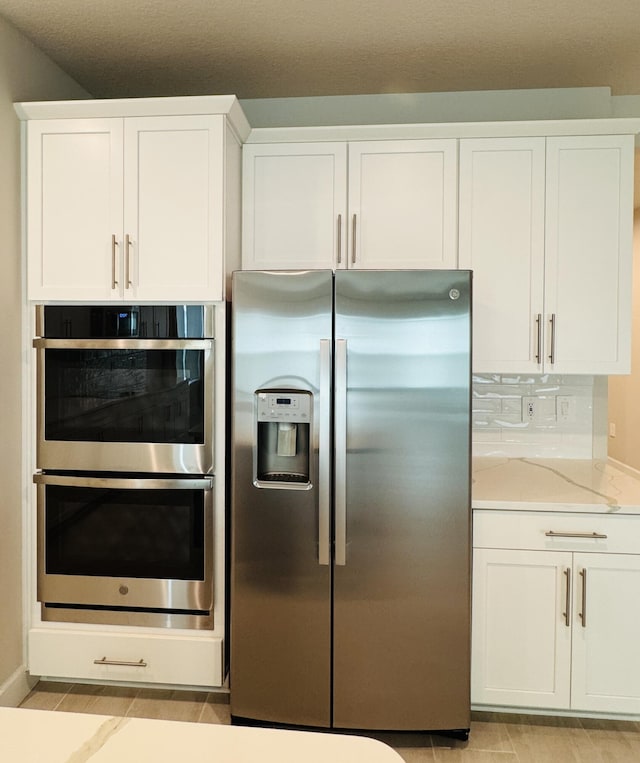 163 SW Pomeroy St, Stuart, FL 34997 - kitchen with appliances with stainless steel finishes, white cabinets, and light stone countertops