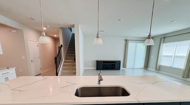 163 SW Pomeroy St, Stuart, FL 34997 - kitchen featuring a sink, open floor plan, a textured ceiling, light stone countertops, and decorative light fixtures
