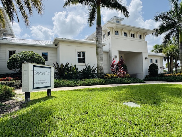 163 SW Pomeroy St, Stuart, FL 34997 - view of front of house with a front yard, stucco siding, a standing seam roof, and metal roof