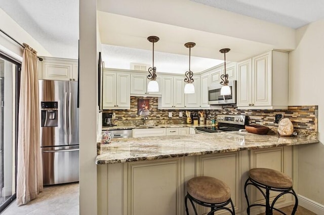 7 Atrium Cir Unit D, Atlantis, FL 33462 - kitchen with appliances with stainless steel finishes, light stone counters, a peninsula, backsplash, and pendant lighting