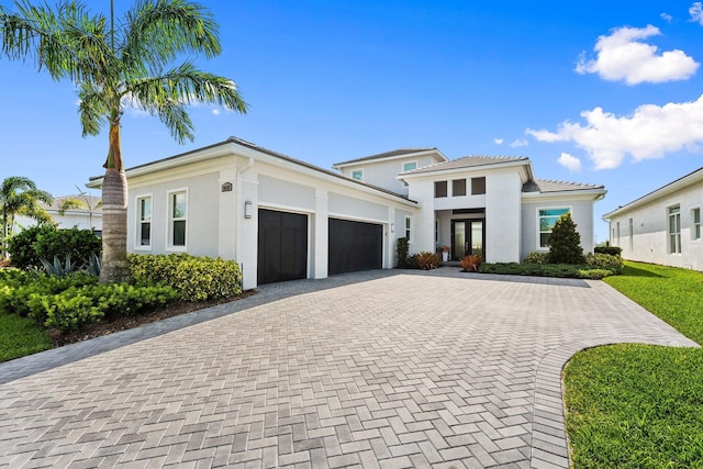 8650 SW Felicita Way, Port Saint Lucie, FL 34987 - view of front of property with an attached garage, decorative driveway, stucco siding, and french doors