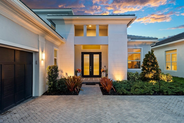8650 SW Felicita Way, Port Saint Lucie, FL 34987 - exterior entry at dusk featuring french doors and an attached garage