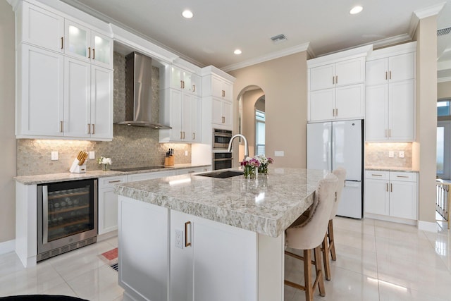 8650 SW Felicita Way, Port Saint Lucie, FL 34987 - kitchen featuring wine cooler, freestanding refrigerator, wall chimney exhaust hood, light tile patterned floors, and crown molding