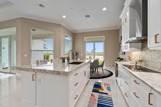 8650 SW Felicita Way, Port Saint Lucie, FL 34987 - kitchen featuring black electric cooktop, wall chimney exhaust hood, light tile patterned floors, an island with sink, and ornamental molding