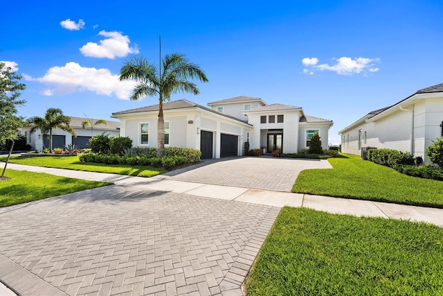 8650 SW Felicita Way, Port Saint Lucie, FL 34987 - view of front of home featuring an attached garage, decorative driveway, a front lawn, and stucco siding