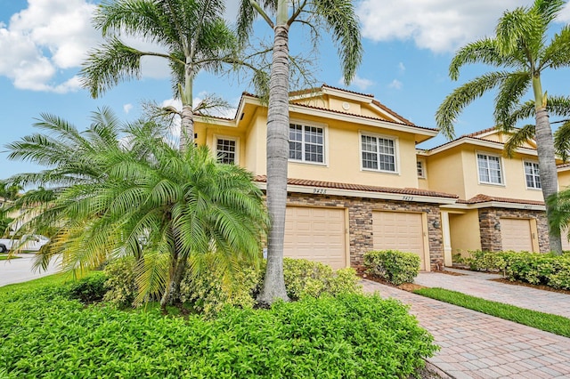 9425 SW Purple Martin Way, Stuart, FL 34997 - view of front of property featuring stone siding, stucco siding, a garage, driveway, and a tiled roof