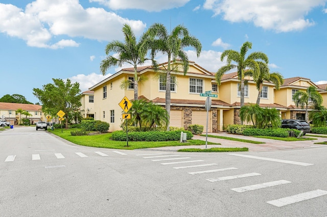 9425 SW Purple Martin Way, Stuart, FL 34997 - townhome / multi-family property with a residential view, an attached garage, stone siding, stucco siding, and driveway