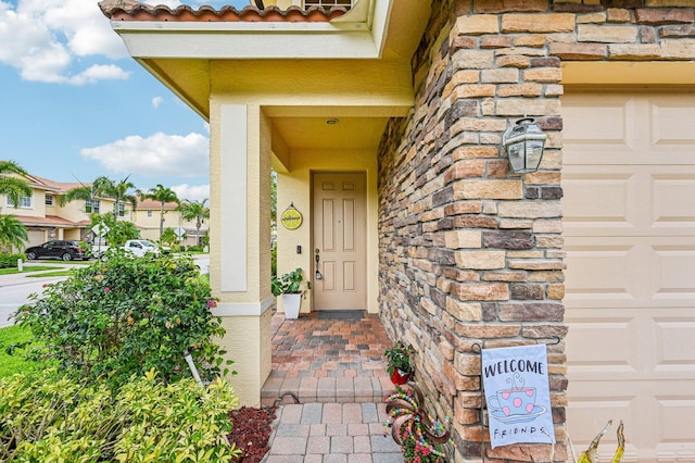 9425 SW Purple Martin Way, Stuart, FL 34997 - property entrance with a garage, stucco siding, a tile roof, and stone siding