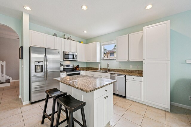 9425 SW Purple Martin Way, Stuart, FL 34997 - kitchen with stainless steel appliances, arched walkways, stone countertops, a center island, and a kitchen breakfast bar