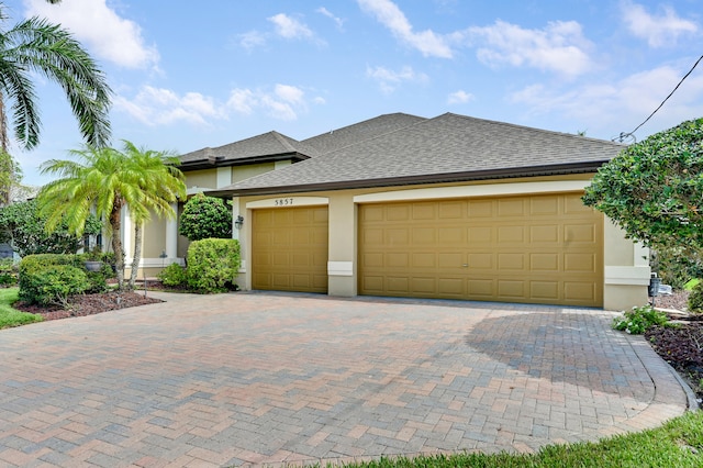 5857 NW Leghorn Ave, Port Saint Lucie, FL 34986 - view of front of property with stucco siding, a shingled roof, decorative driveway, and an attached garage