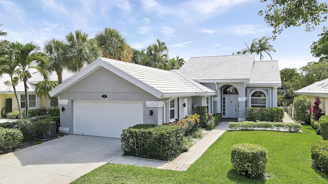 1365 Wilderness Rd, West Palm Beach, FL 33409 - view of front of house featuring a garage, a front lawn, stucco siding, concrete driveway, and a tiled roof