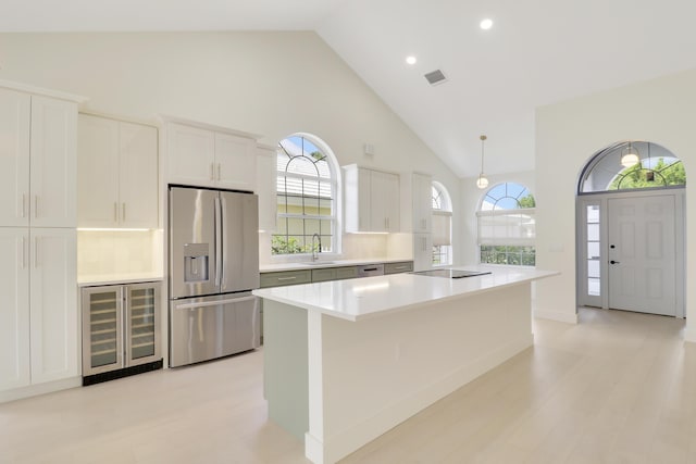 1365 Wilderness Rd, West Palm Beach, FL 33409 - kitchen featuring stainless steel refrigerator with ice dispenser, wine cooler, high vaulted ceiling, light countertops, and white cabinetry