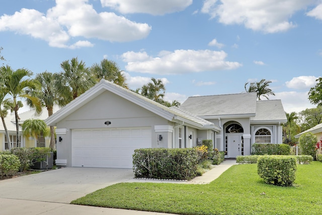 1365 Wilderness Rd, West Palm Beach, FL 33409 - view of front facade featuring an attached garage, a front yard, driveway, and stucco siding