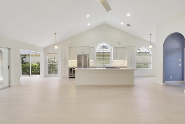 1365 Wilderness Rd, West Palm Beach, FL 33409 - unfurnished living room with high vaulted ceiling, arched walkways, light wood-type flooring, wine cooler, and recessed lighting
