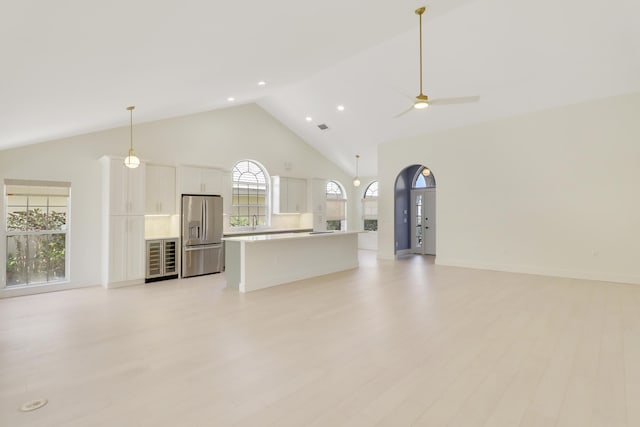 1365 Wilderness Rd, West Palm Beach, FL 33409 - unfurnished living room with high vaulted ceiling, light wood-style floors, beverage cooler, ceiling fan, and recessed lighting