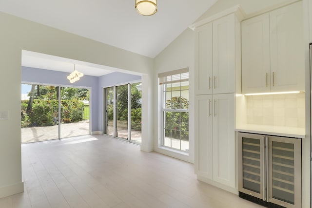 1365 Wilderness Rd, West Palm Beach, FL 33409 - unfurnished living room with beverage cooler, a chandelier, light wood-type flooring, and high vaulted ceiling