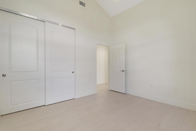 1365 Wilderness Rd, West Palm Beach, FL 33409 - unfurnished bedroom featuring light wood finished floors, high vaulted ceiling, and a closet