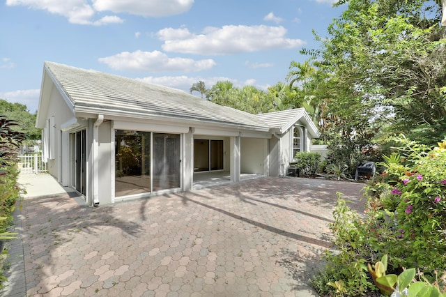 1365 Wilderness Rd, West Palm Beach, FL 33409 - view of side of property with a patio, a tile roof, and stucco siding