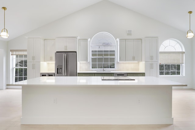 1365 Wilderness Rd, West Palm Beach, FL 33409 - kitchen with stainless steel fridge with ice dispenser, light countertops, stovetop, a spacious island, and hanging light fixtures