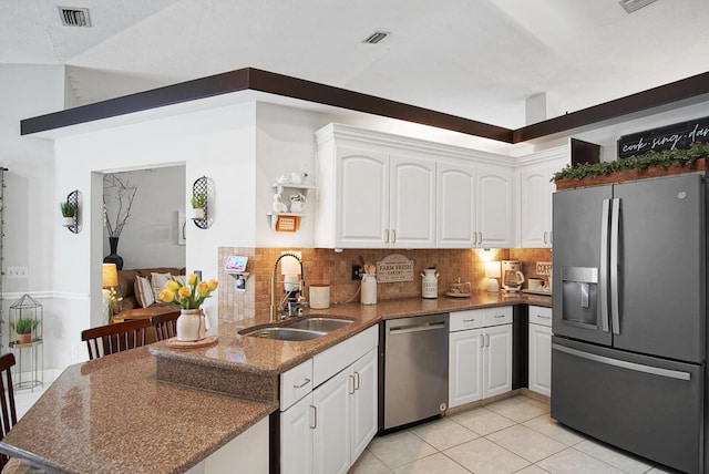 3283 SE W Snow Rd, Port Saint Lucie, FL 34984 - kitchen featuring stainless steel appliances, white cabinetry, a peninsula, decorative backsplash, and light tile patterned floors