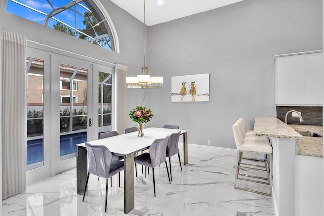 20677 NW 26th Ct, Boca Raton, FL 33434 - dining room featuring a high ceiling, a chandelier, light marble finish flooring, french doors, and baseboards