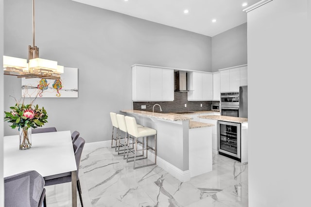 20677 NW 26th Ct, Boca Raton, FL 33434 - kitchen featuring wall chimney exhaust hood, beverage cooler, a towering ceiling, a chandelier, and black stovetop