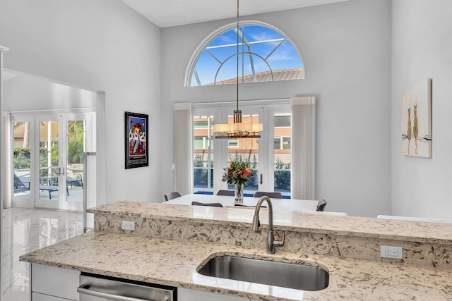 20677 NW 26th Ct, Boca Raton, FL 33434 - kitchen with a sink, a towering ceiling, light stone counters, hanging light fixtures, and french doors