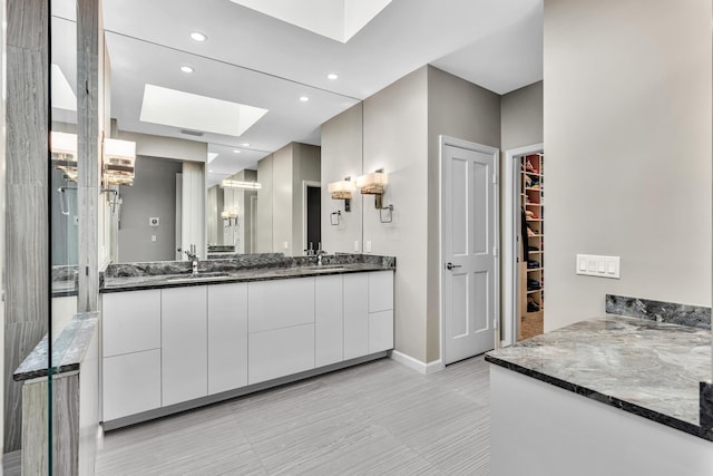 20677 NW 26th Ct, Boca Raton, FL 33434 - bathroom with a skylight, double vanity, a spacious closet, baseboards, and recessed lighting