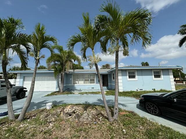 1209 N Australian Ave, West Palm Beach, FL 33401 - ranch-style home featuring an attached garage, concrete driveway, and stucco siding