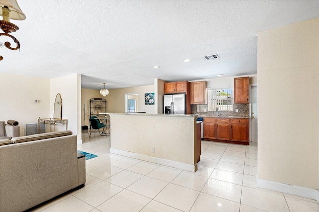 1209 N Australian Ave, West Palm Beach, FL 33401 - kitchen with stainless steel fridge, brown cabinetry, a textured ceiling, decorative backsplash, and light tile patterned floors
