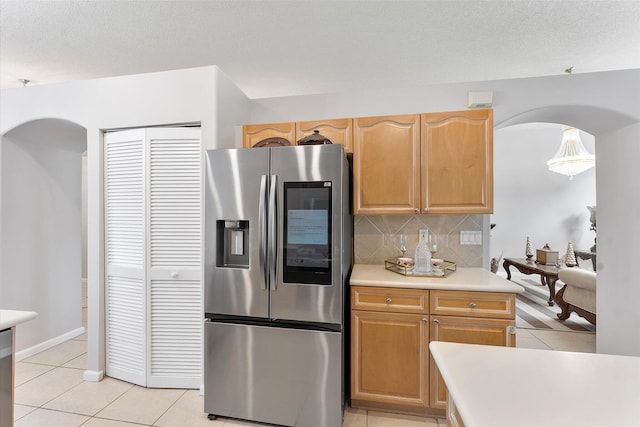 8073 Pelican Harbour Dr, Lake Worth, FL 33467 - kitchen featuring stainless steel fridge with ice dispenser, arched walkways, light tile patterned floors, backsplash, and light countertops